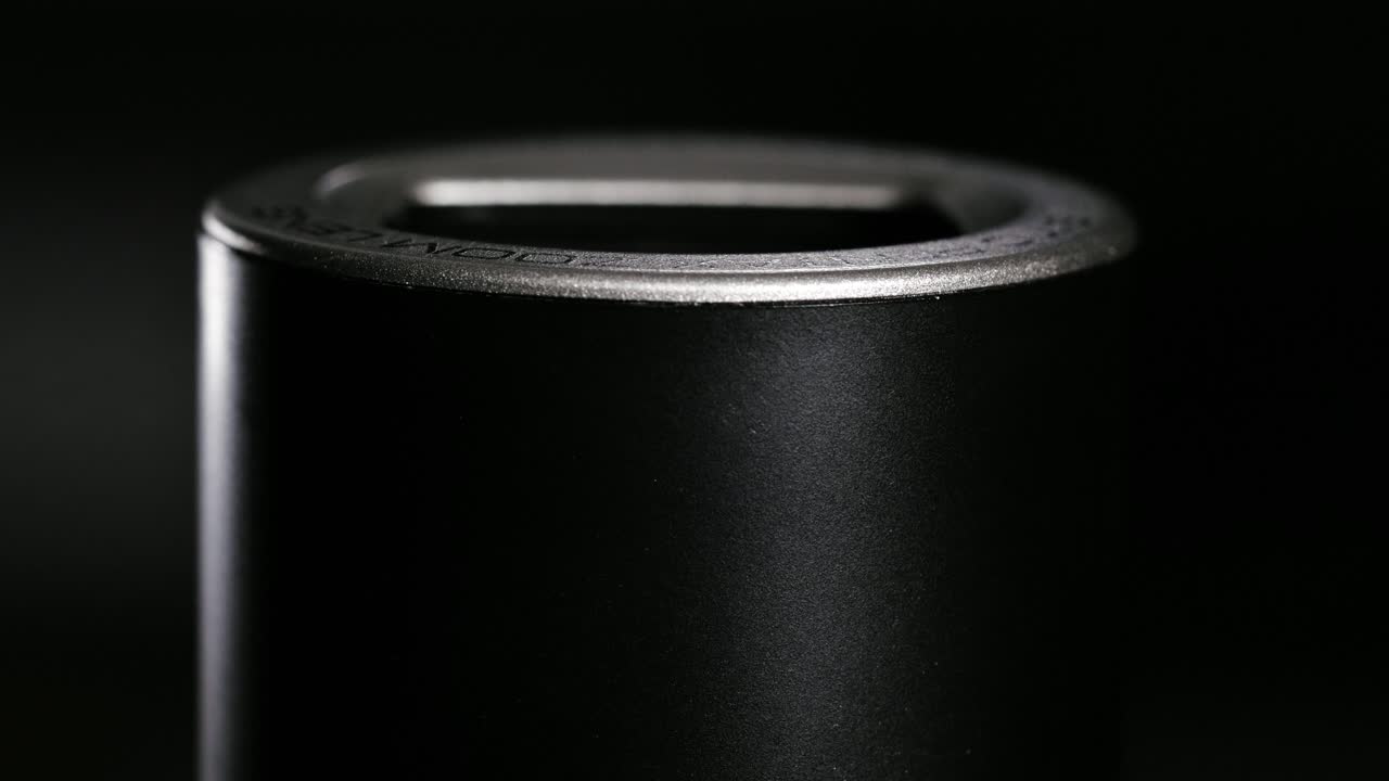 Macro of black and silver zoom barrel retracting into dark space and extending again