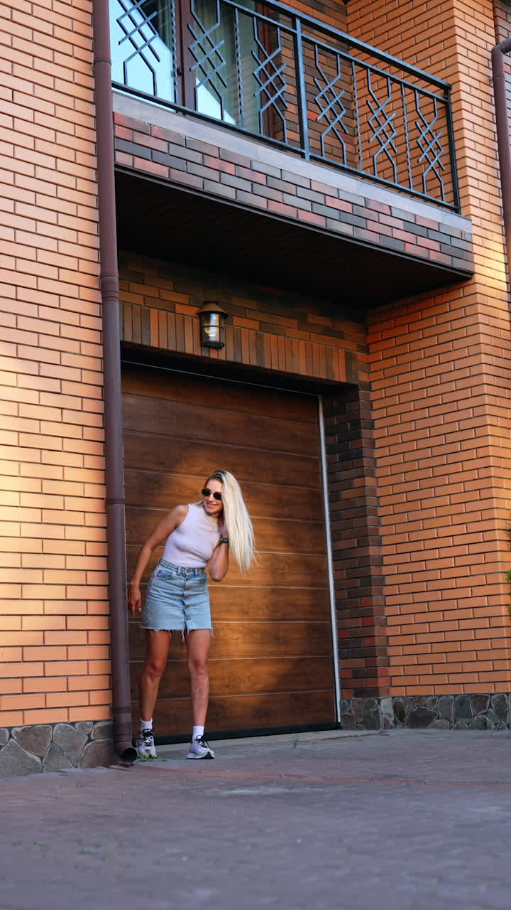Woman happily greets child at home. A woman in sunglasses smiles while a child runs towards her at a brown brick house entrance during sunset