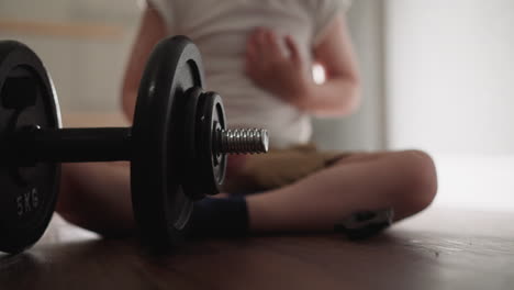 Adorable-little-boy-sits-on-floor-spinning-gear-on-barbell