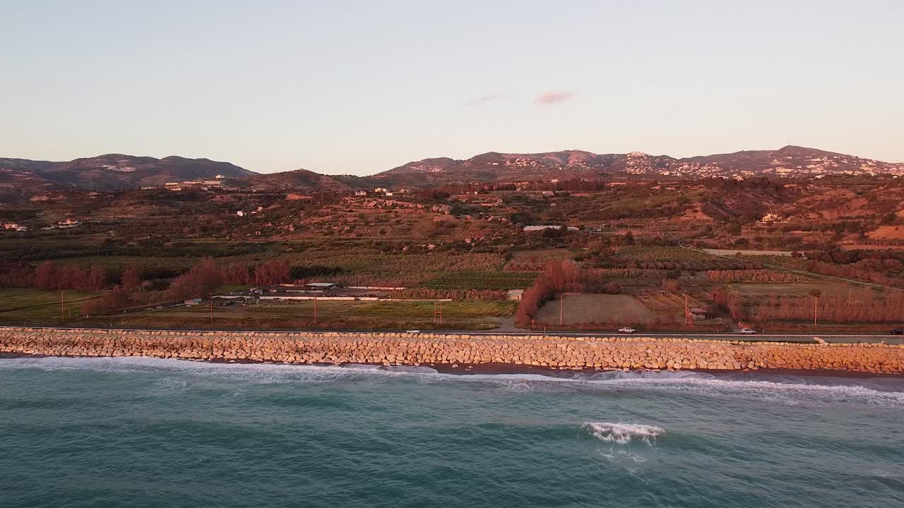 imágenes de drones capturando una serena puesta de sol sobre una carretera costera en chipre, con colinas onduladas y el mar mediterráneo a la vista