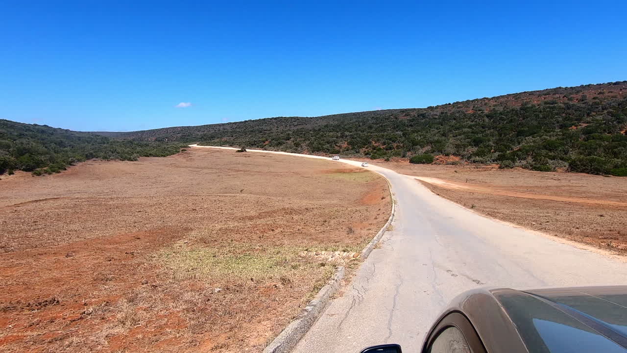 남아프리카 공화국의 언덕을 통해 먼 먼지투성이 도로를 따라 운전하는 자동차의 pov