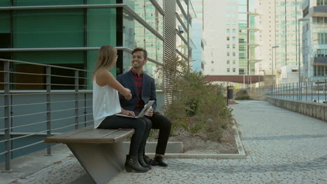 Business-people-using-laptop-and-shaking-hands-outdoor