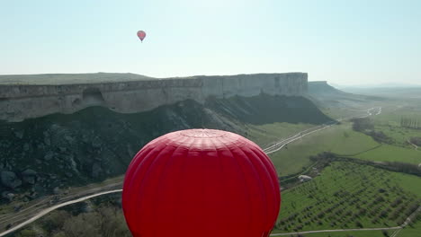 hot air balloon ride over a valley with mountains and a cliff