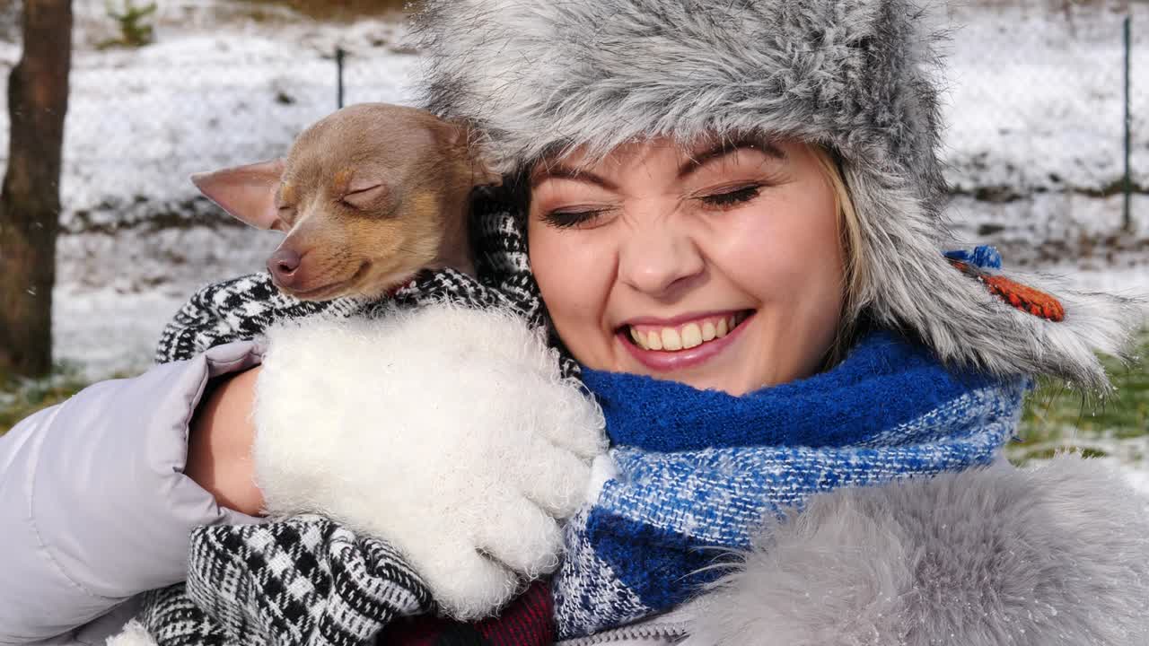 여자 는 겨울 밖 에서 작은 개 와 함께 놀고 있다