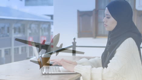 animation of asian woman in hijab using laptop over cityscape