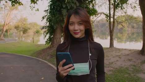 woman using phone in park wearing mask