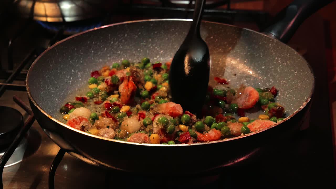 Mixing frozen vegetables on the hot pan with plastic spoon