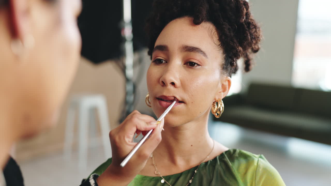 un maquillador aplicando lápiz labial a una modelo