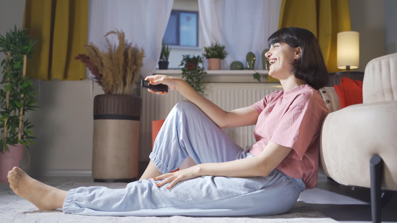 tv에서 코미디를 보는 여자가 웃습니다.