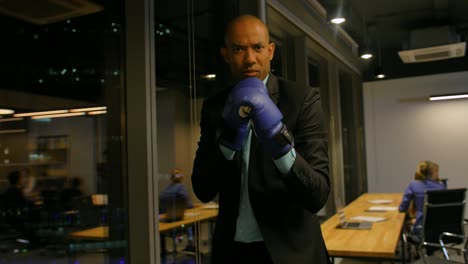 ready to business fight concept. african boxer in gloves and formal suit waving with his boxing gloves