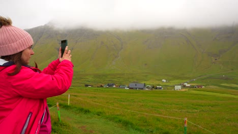 turista filmando el paisaje de las islas feroe con una cámara de teléfono en la aldea de gasadalur, islas feroe