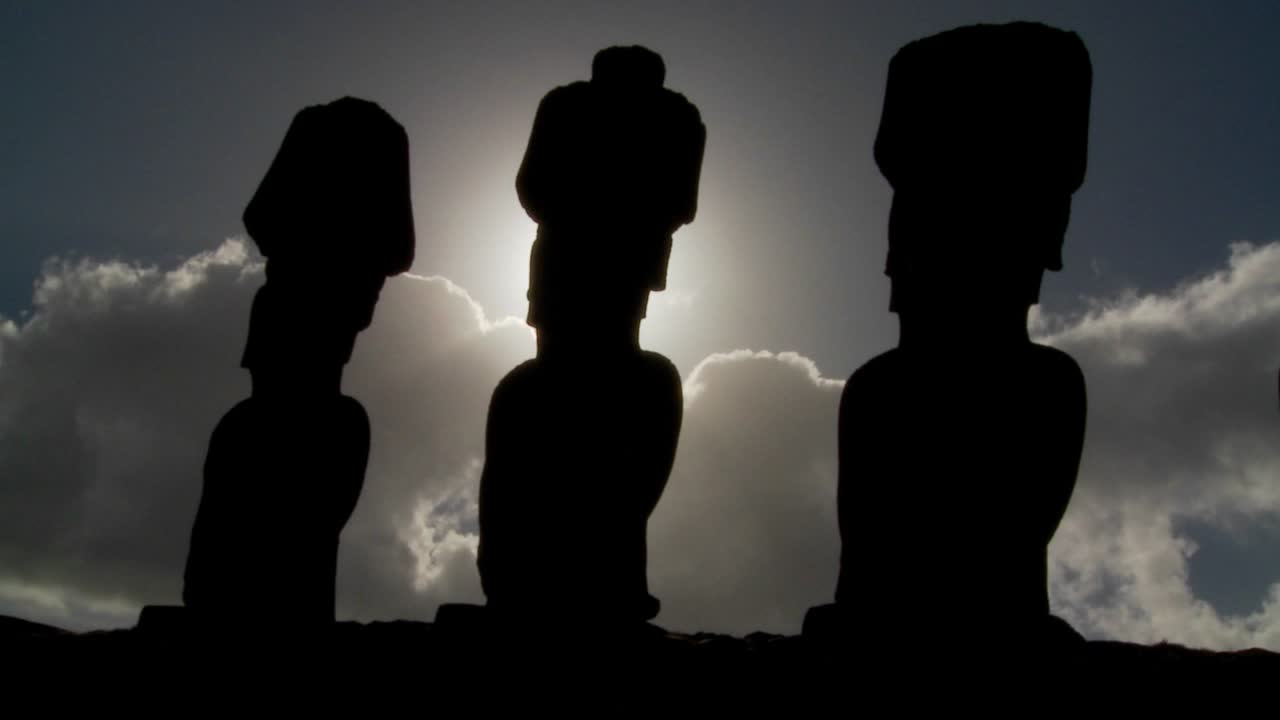 이스터 섬 조각상은 태양을 배경으로 실루엣입니다.