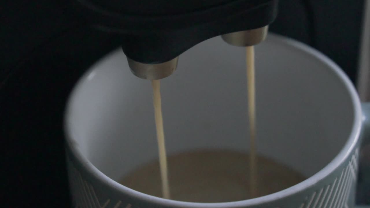 Coffee coming out of a coffee machine into a cup.