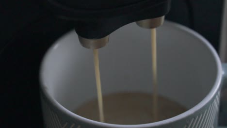 coffee coming out of a coffee machine into a cup.