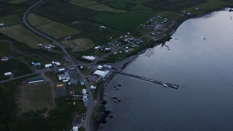 Borgarfjordur-concrete-docking-pier-in-calm-fjord-at-night,-aerial