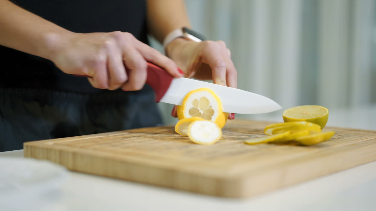 Female hands cutting fresh juicy lemon on a wooden kitchen board. Healthy lifestyle. Fresh fruits.