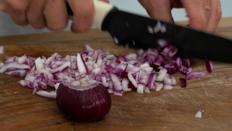 cortar en cubitos una cebolla roja en preparación para saltear en una tabla para cortar