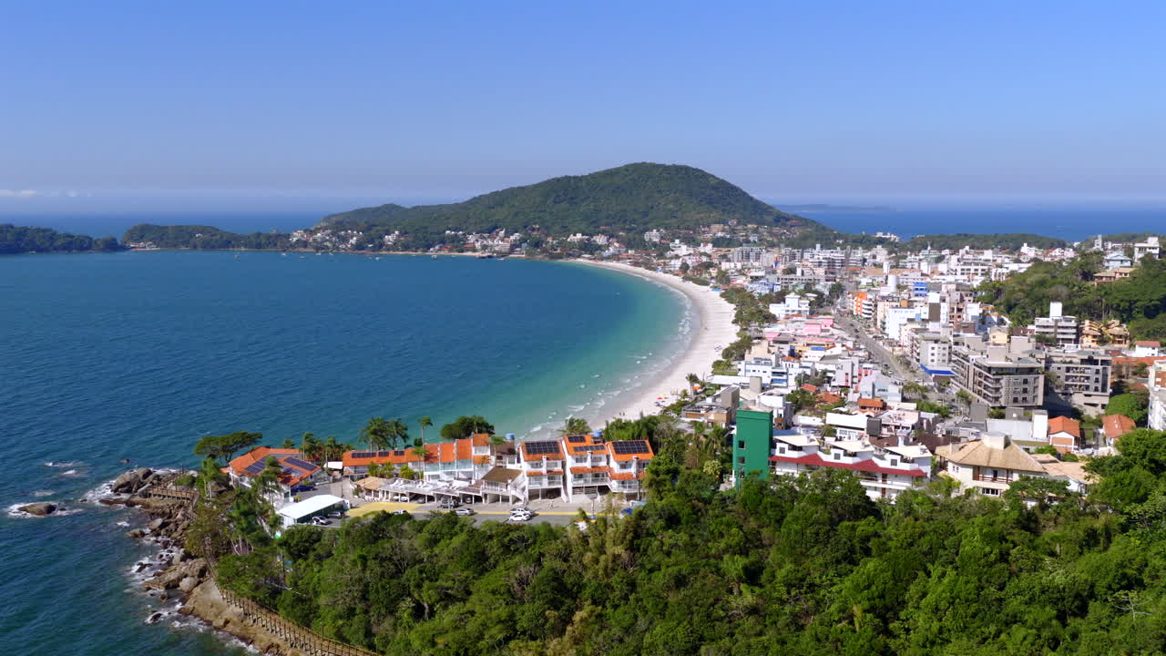Drone shot of Bombas Beach with turquoise waters, sandy shore, and coastal cityscape