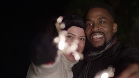 man and woman waving sparklers