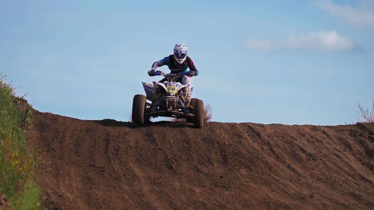 극단적인 슬로우 모션으로 흙길 트레일의 경사면에서 점프하는 쿼드 레이서 1명