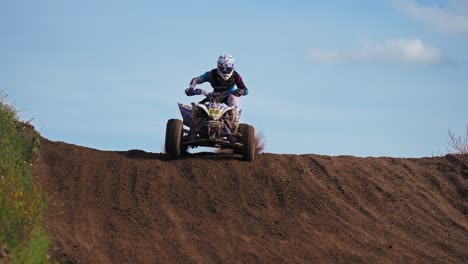 one quad racer jumping from slope on dirt road trail in extreme slow motion