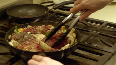 cocinar una comida coreana con carne y diferentes ingredientes arrojados sobre la sartén