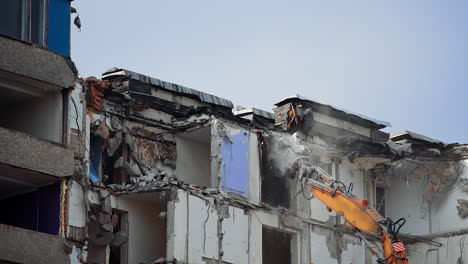 destruction machine demolishes the ruined building. pieces of concrete falling down from the roof of the destroyed house. cleaning the site for the new construction.