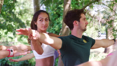 Female-Instructor-Helping-Students-At-Outdoor-Yoga-Class