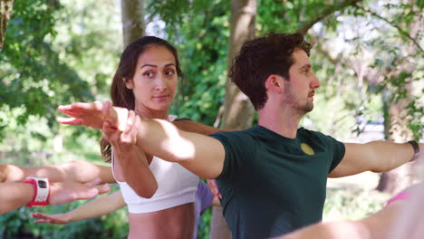 instructora ayudando a los estudiantes en una clase de yoga al aire libre