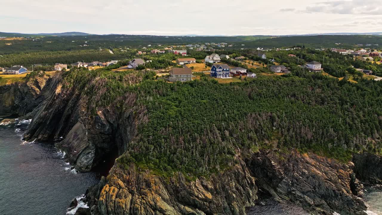 A drone glides along Torbay's dramatic coastline, revealing sheer rock walls dropping into the Atlantic and a small coastal community perched above green hills