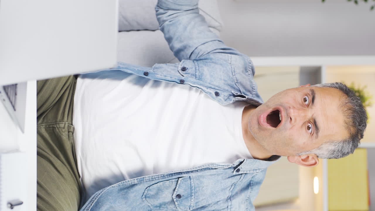 Video verticale di un uomo che guarda un laptop con stupore