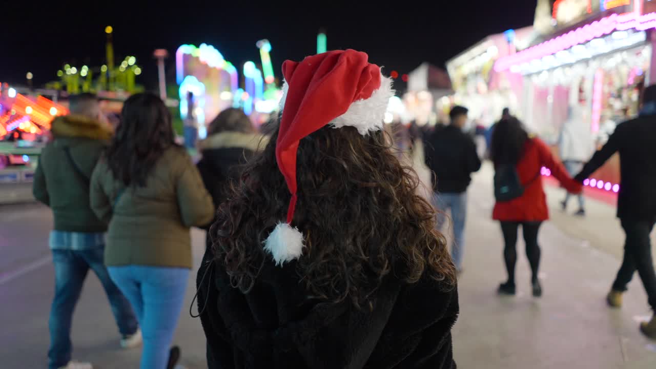 Woman in Santa Hat at a Nighttime Fair