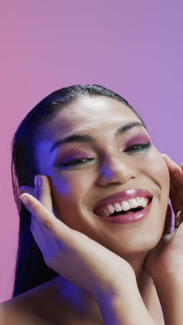 vertical video of biracial woman with black hair and make up touching face, copy space, slow motion