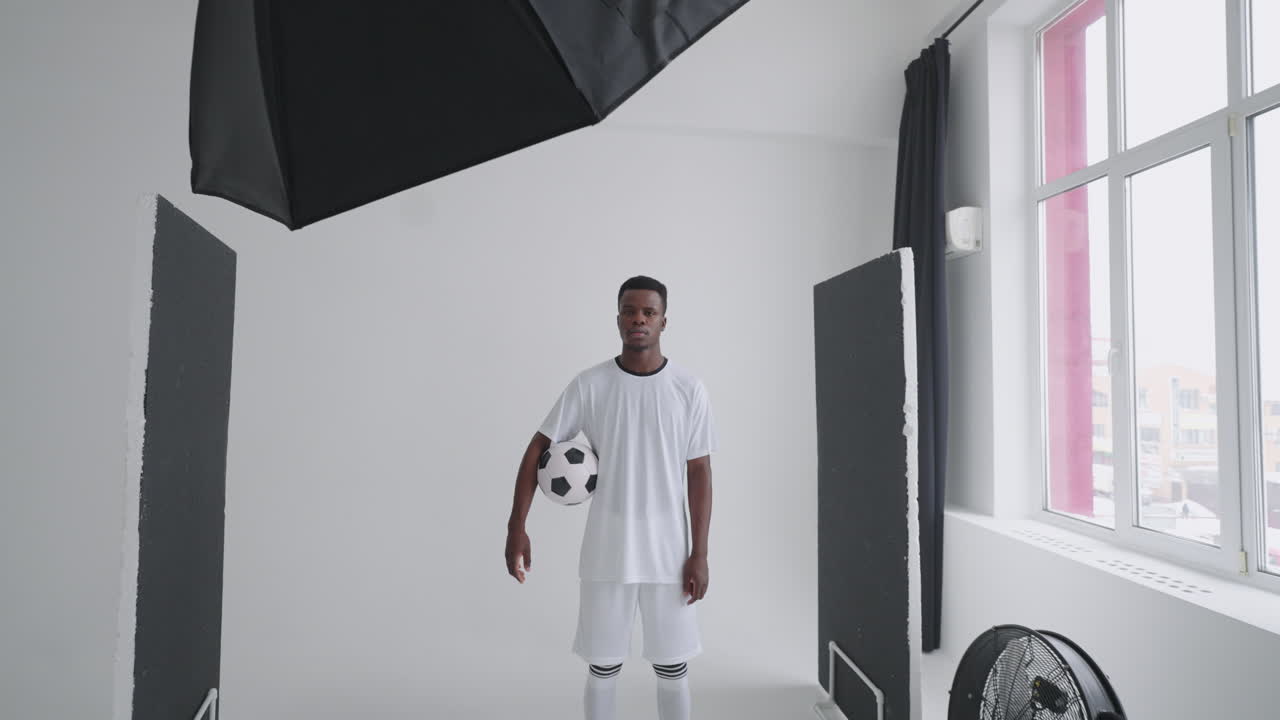 Art director checking the photos on a monitor. Professional crew team together in the studio. Behind the scene of photo shooting Professional football player and production set up in the big studio.