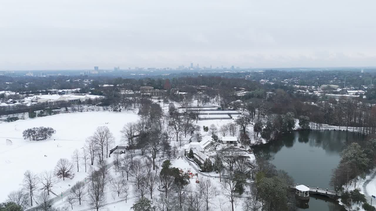 Aerial push in on Piedmont Park and Downtown Atlanta covered in snow.