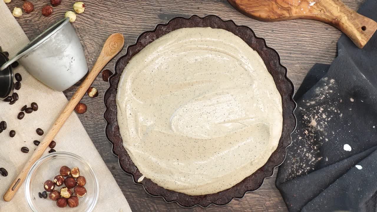 A delicious dessert, Coffee Hazelnut Cream Tart. Made with espresso powder, chocolate crust and loaded with crushed hazelnut. Using a spatula to spread out the batter before putting in the oven