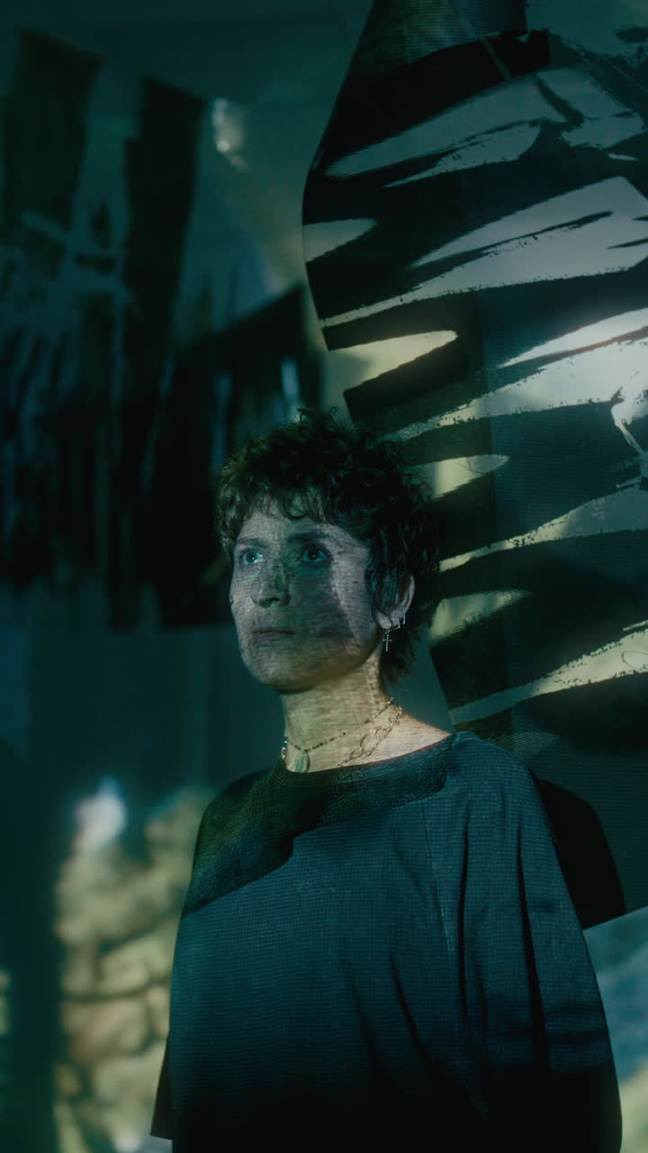 Young Woman Watching Abstract Light Projection in Dark Room