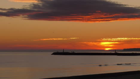 coastal sunrise, dawn skies over calm sea and harbor wall