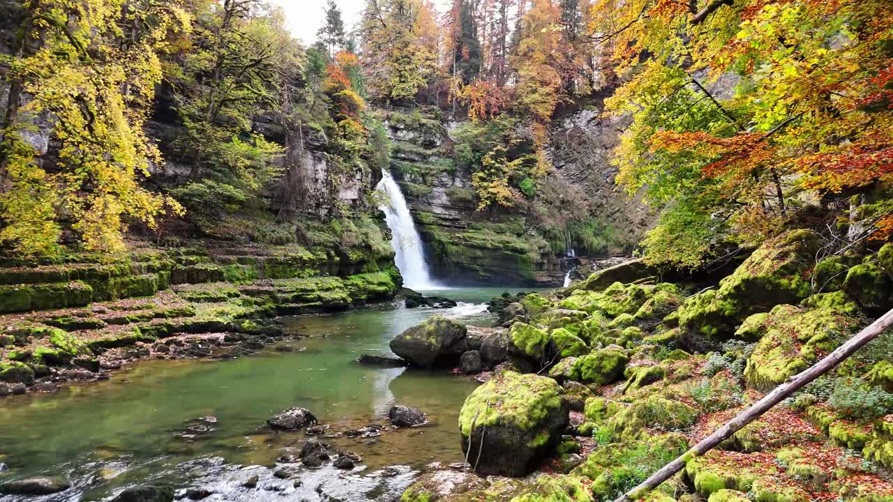 Plano de drone seguindo o rio em direção à cachoeira Saut du Doubs no Rio Doubs entre Villers-le-Lac em Doubs, Bourgogne-Franche-Comté, França e Les Brenets na Suíça