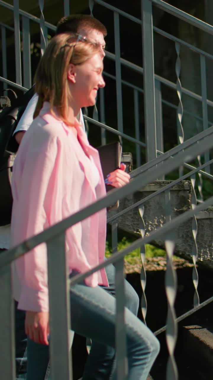 estudiantes subiendo escaleras al aire libre en un entorno urbano, interactuando cálidamente mientras llevan mochilas, la luz del sol proyectando sombras en barandillas metálicas, capturando conversación casual y conexión