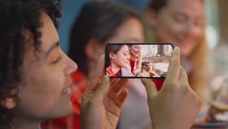 Woman-Taking-Video-Of-Friends-On-Camping-Holiday-In-Forest-Lying-In-Tent-Eating-S'mores