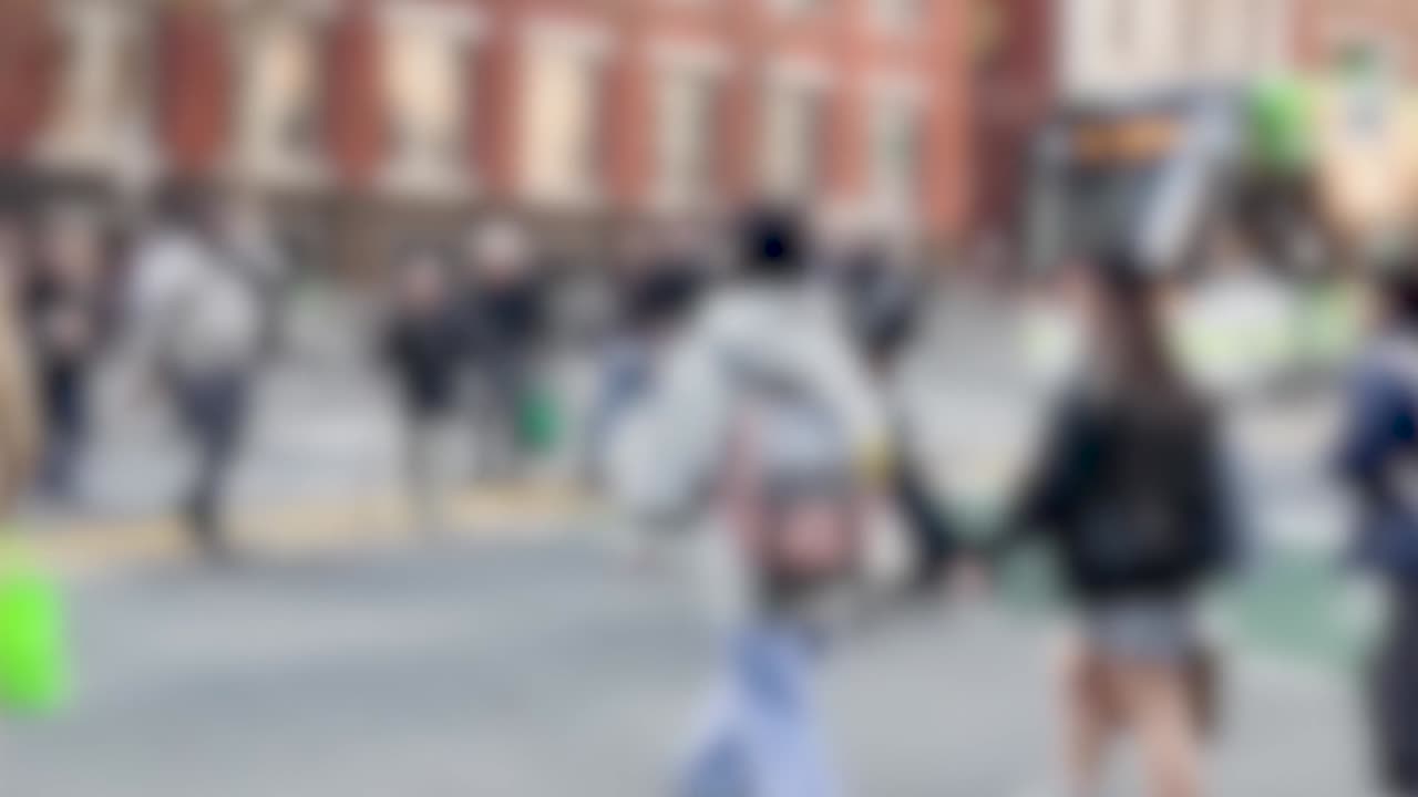 Pedoni sfocati camminano su una strada cittadina con sfocatura di movimento alla luce del giorno.