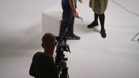 toma aérea de un operador de cámara de película masculino enfocando la cámara usando un monitor filmando o grabando video en el estudio 1