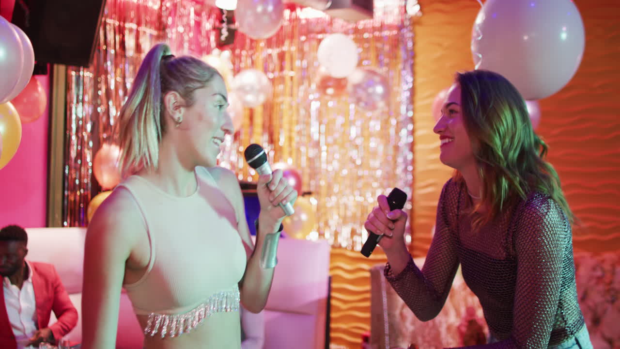 Video of two happy caucasian female friends singing karaoke at a nightclub