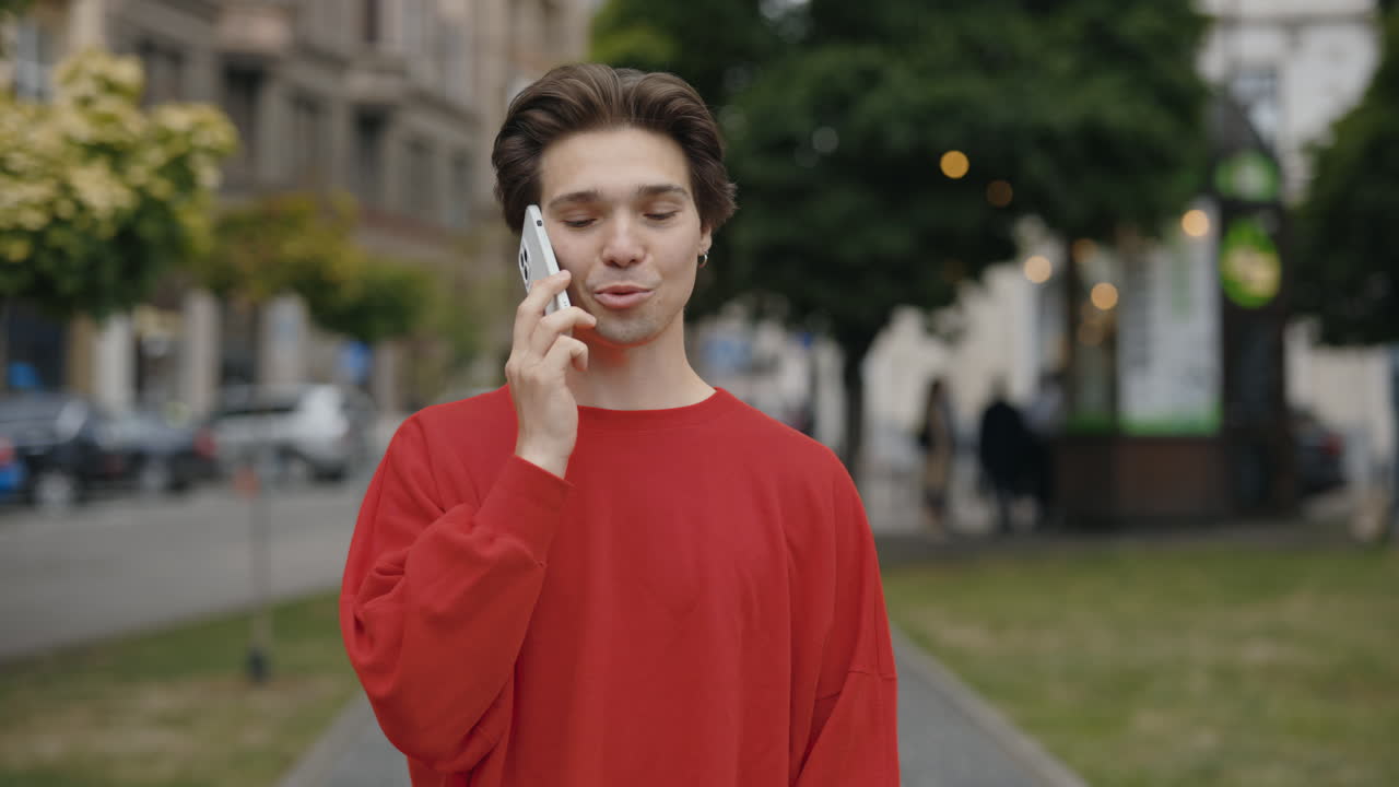 Man in Red Sweatshirt Talking on Phone in City
