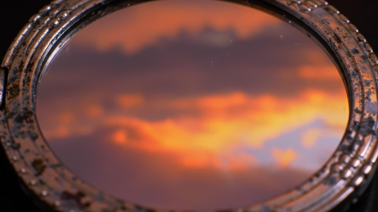A Captivating Reflection: The Subtle Beauty of a Vintage Circular Mirror Displaying a Dreamy Sunset Sky in Soft Hues of Orange and Purple