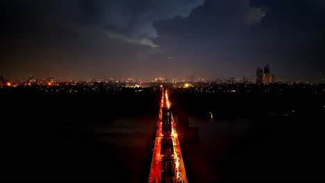 long bien bridge with traffic in hanoi and lightning in sky, night drone view