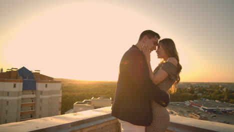 Young-couple-in-love-standing-on-the-roof-hug-and-closely-look-at-each-other.-Romantic-evening-on-the-roof-of-the-building.-A-date-on-the-roof-of-a-building-love.-Slow-motion