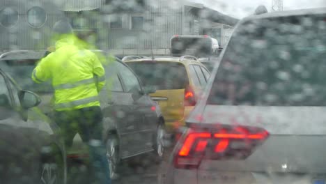 雨天車輛在交通中等待,黃色外套的男人指引司機