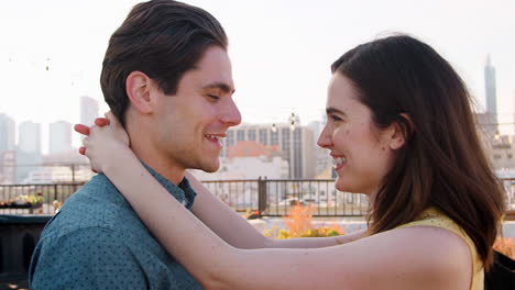 romantic couple hugging on rooftop terrace with city skyline in background